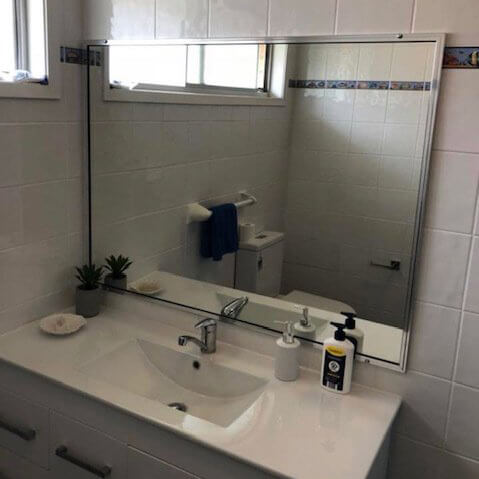 Side view of bathroom with white wash basin and simple mirror on wall
