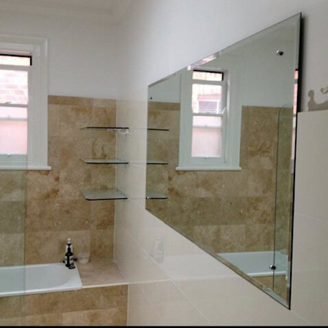 Bathroom with bathtub, showerscreen, glass shelves and simple mirror on a wall